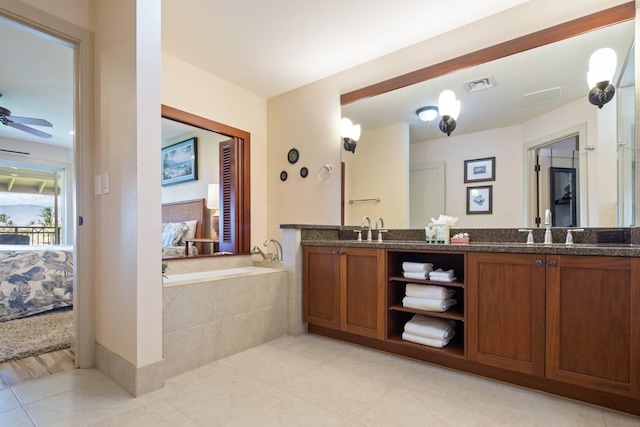 bathroom with tile patterned flooring, vanity, tiled bath, and ceiling fan