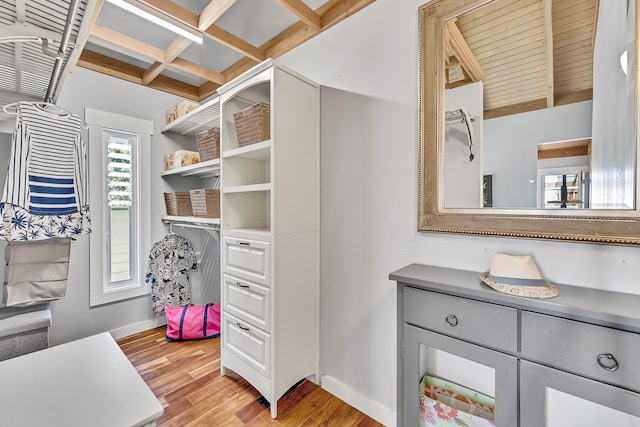 spacious closet featuring beamed ceiling, coffered ceiling, and light wood-type flooring