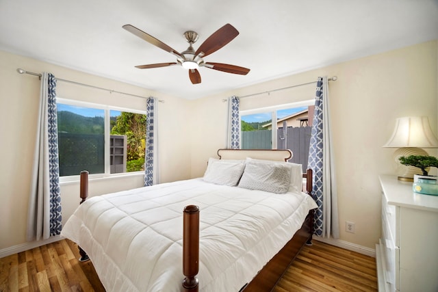 bedroom with baseboards, multiple windows, and wood finished floors
