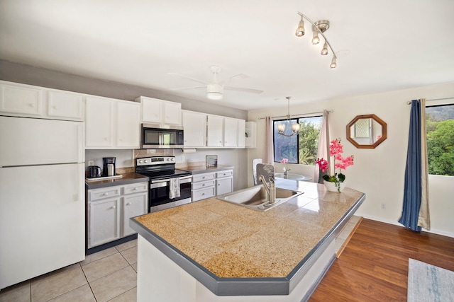 kitchen featuring a sink, tile countertops, white cabinetry, a ceiling fan, and stainless steel appliances