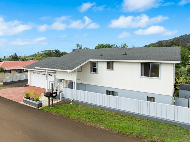 view of front of property featuring concrete driveway, an attached garage, fence, and a shingled roof