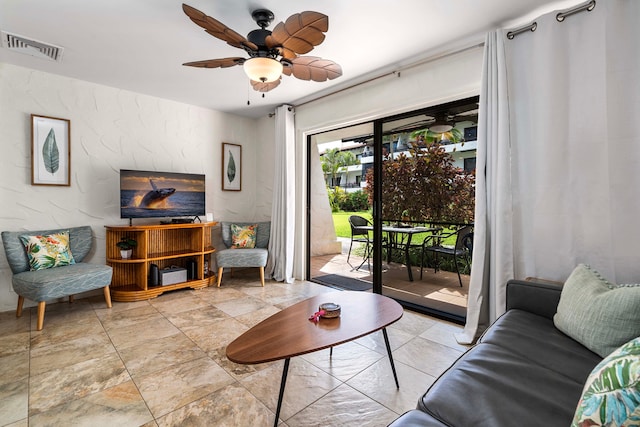 living area featuring ceiling fan, a textured wall, and visible vents