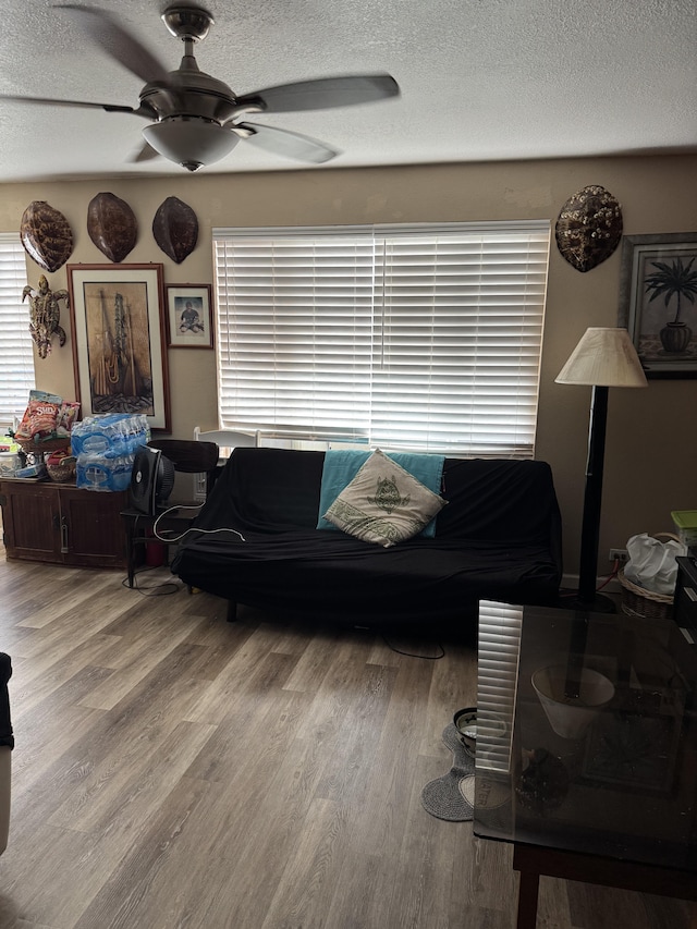 living room featuring ceiling fan, hardwood / wood-style floors, and a textured ceiling