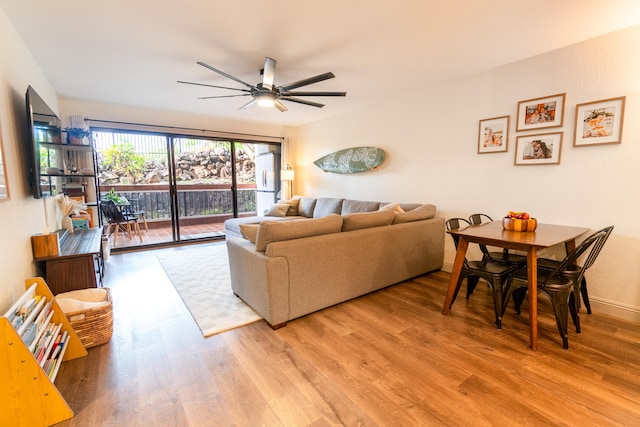 living area with baseboards, ceiling fan, and light wood finished floors