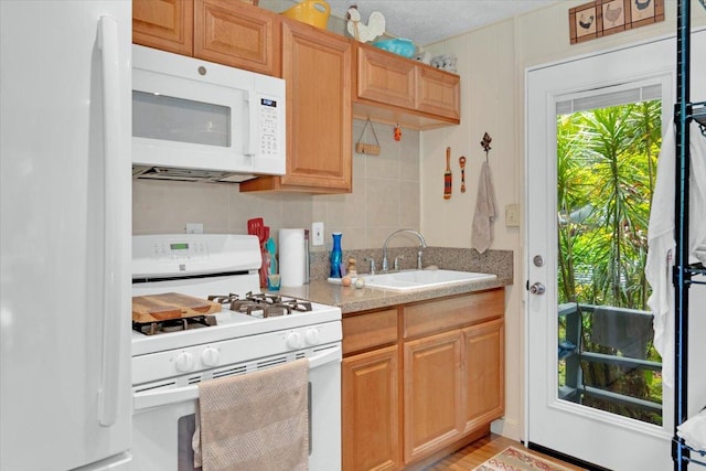 kitchen with light countertops, white appliances, and a sink