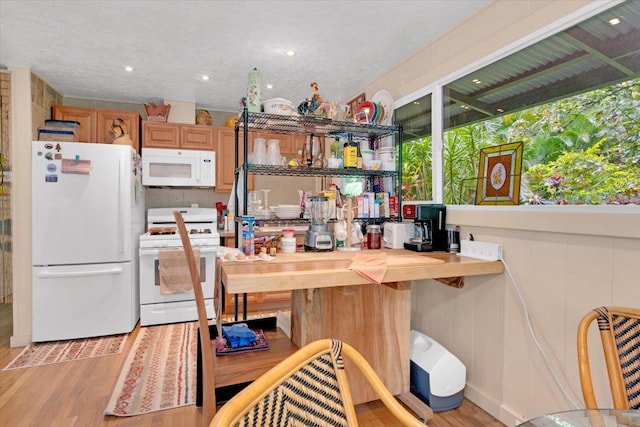 kitchen featuring brown cabinetry, white appliances, and light wood finished floors
