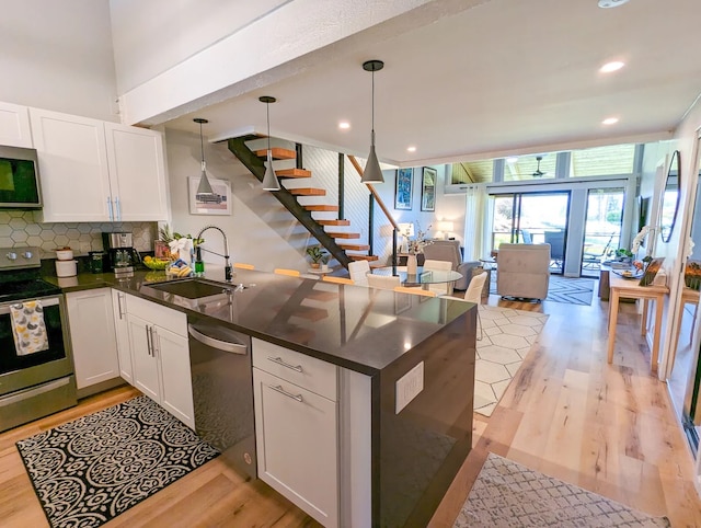 kitchen featuring sink, white cabinetry, stainless steel appliances, and decorative light fixtures