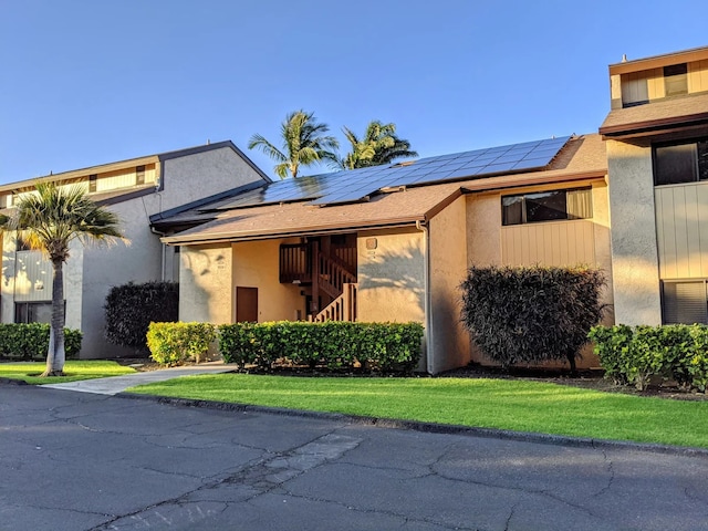 view of front of house with solar panels and a front lawn