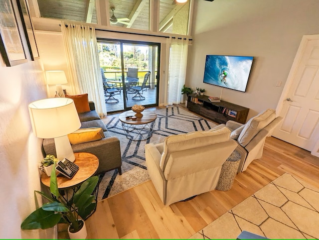 living room with ceiling fan, high vaulted ceiling, and wood-type flooring