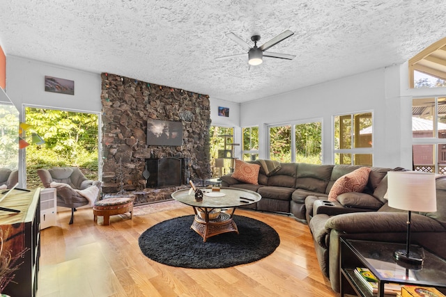 living room featuring a healthy amount of sunlight, a textured ceiling, a fireplace, and wood finished floors