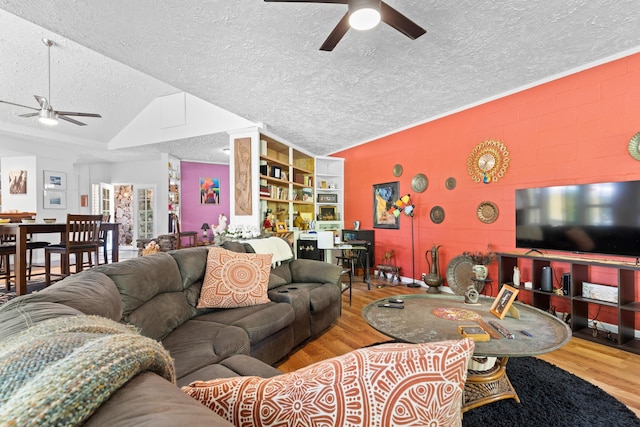 living area with concrete block wall, lofted ceiling, a ceiling fan, a textured ceiling, and wood finished floors