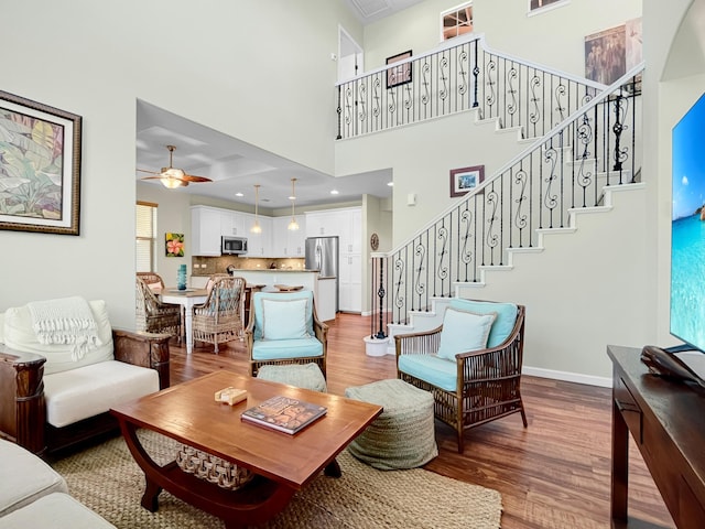 living area featuring ceiling fan, light wood finished floors, stairway, and baseboards