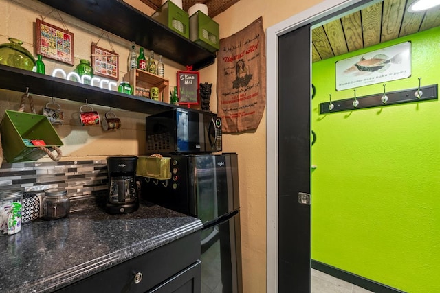 kitchen featuring open shelves, black microwave, decorative backsplash, and dark stone countertops