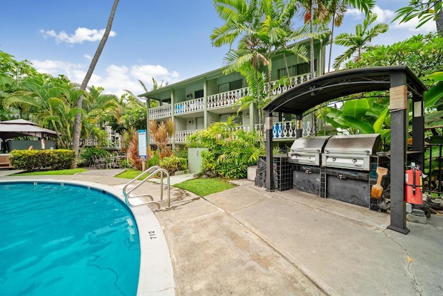 pool featuring exterior kitchen, a patio area, and a grill