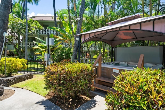 exterior space with a hot tub, fence, and a gazebo