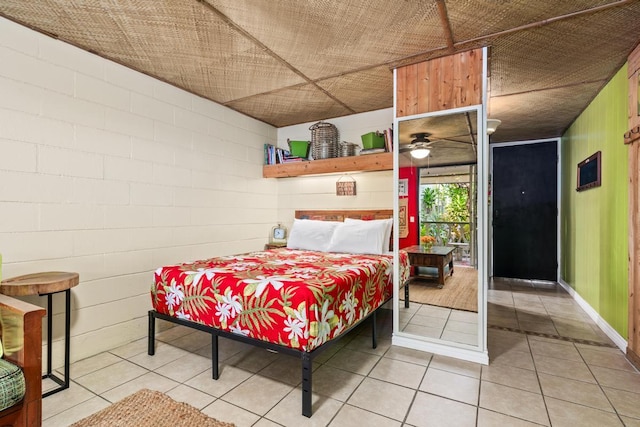 bedroom with concrete block wall and light tile patterned flooring