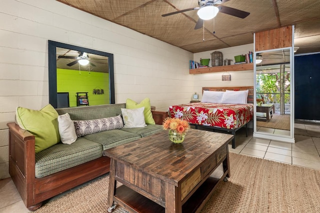 bedroom with concrete block wall, ceiling fan, and tile patterned floors