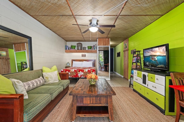 living room with a ceiling fan and concrete block wall