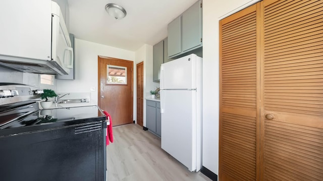 kitchen with white fridge, electric range, sink, and light hardwood / wood-style flooring