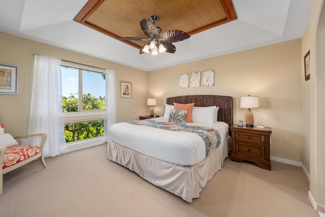 bedroom with a tray ceiling, baseboards, carpet, and ceiling fan