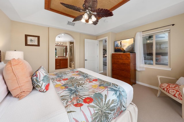 bedroom featuring visible vents, a tray ceiling, arched walkways, carpet floors, and baseboards