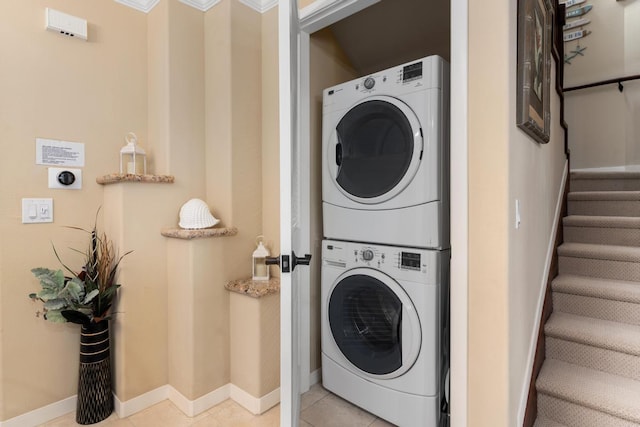 washroom with light tile patterned floors, baseboards, and stacked washing maching and dryer