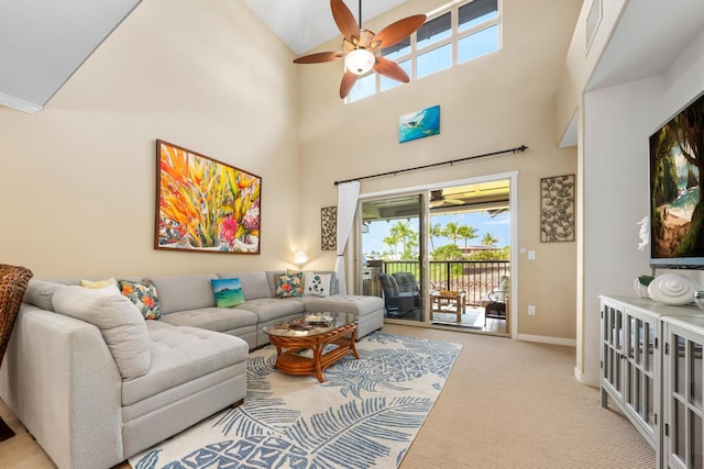 living room with carpet flooring, a ceiling fan, baseboards, and a towering ceiling