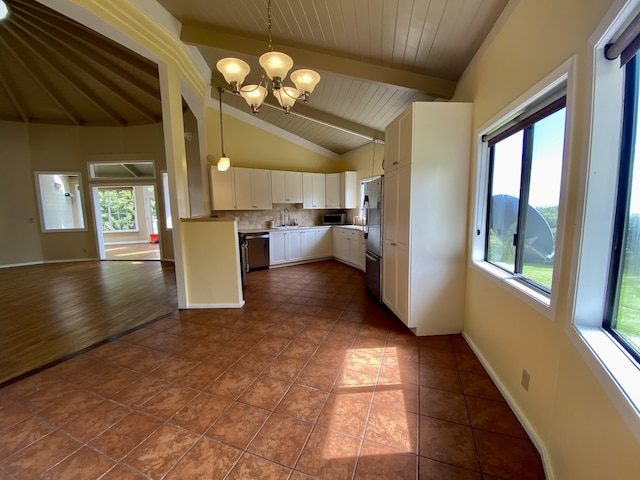 kitchen featuring white cabinetry, lofted ceiling with beams, hanging light fixtures, appliances with stainless steel finishes, and a notable chandelier