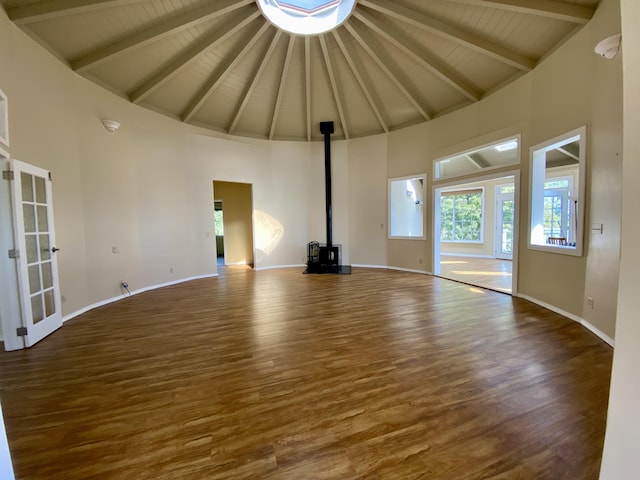 unfurnished living room with high vaulted ceiling, a wood stove, dark hardwood / wood-style flooring, wood ceiling, and beam ceiling