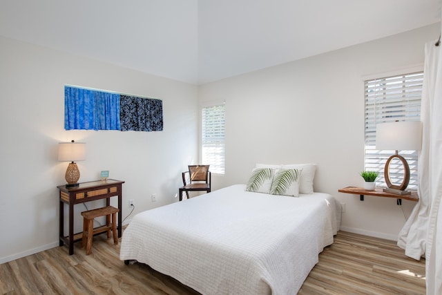 bedroom with baseboards, multiple windows, and light wood-style floors