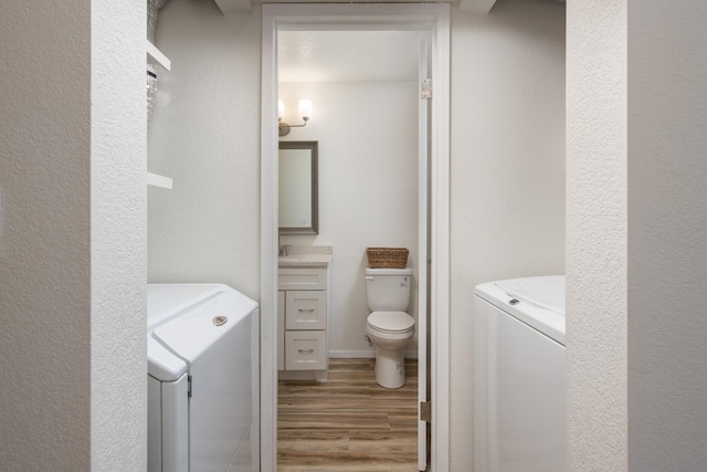 bathroom with toilet, vanity, separate washer and dryer, and wood finished floors