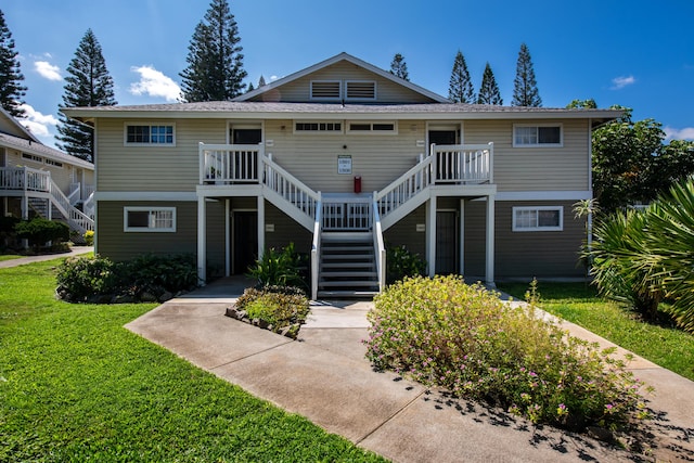 raised beach house with a front lawn and stairs