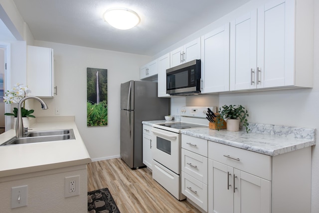 kitchen with light wood finished floors, white electric range, stainless steel microwave, white cabinetry, and a sink