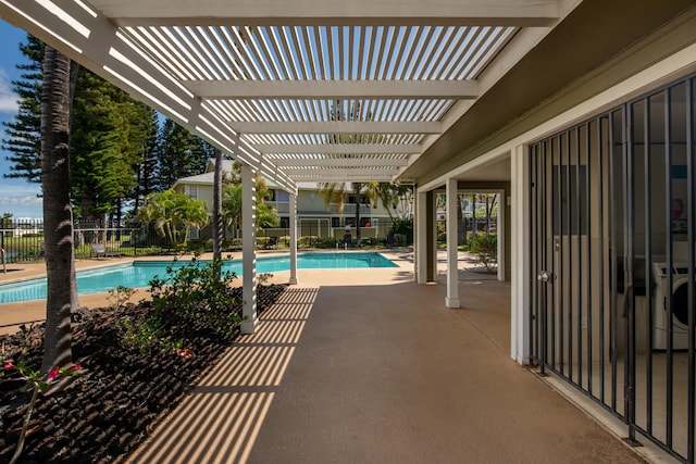 view of patio with washer / dryer, fence, a community pool, and a pergola