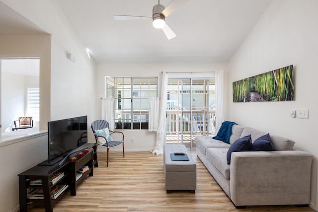 living room with light wood finished floors, baseboards, vaulted ceiling, and a ceiling fan