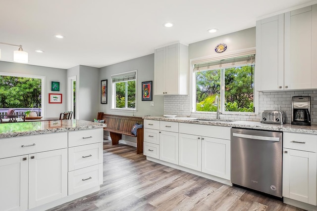 kitchen with light stone countertops, white cabinetry, light wood finished floors, and dishwasher