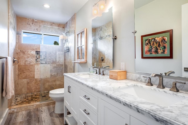 full bath featuring double vanity, wood finished floors, a sink, and toilet