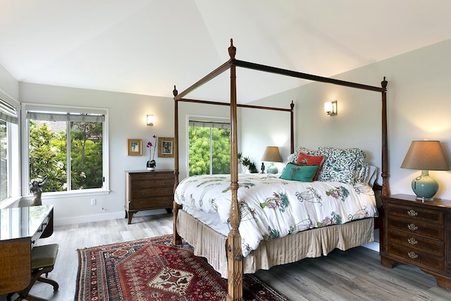 bedroom with multiple windows, vaulted ceiling, and light wood-style flooring