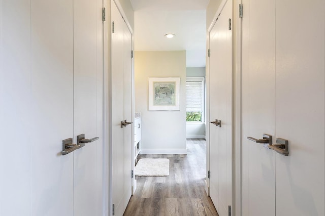 hall featuring light wood-style flooring and baseboards