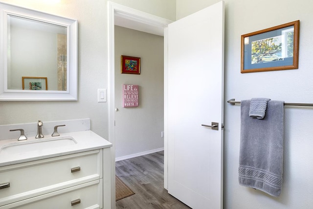 bathroom with wood finished floors, vanity, and baseboards