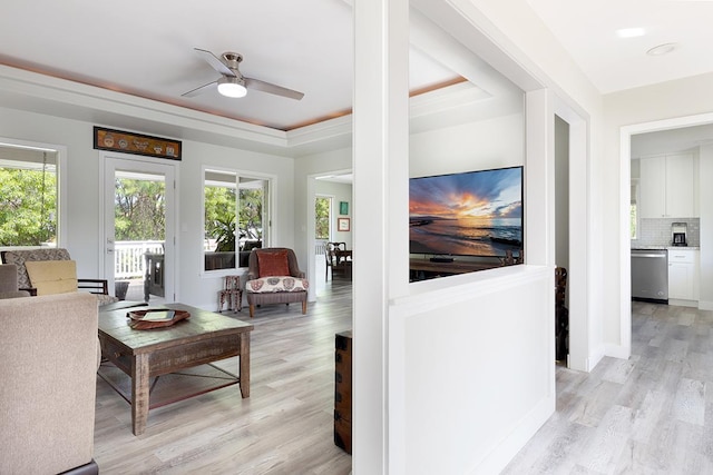 living room with light wood finished floors, a raised ceiling, a ceiling fan, and baseboards