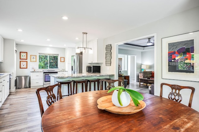 dining room with a ceiling fan, recessed lighting, a raised ceiling, and light wood finished floors