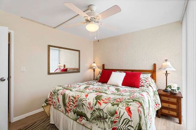 bedroom featuring ceiling fan, baseboards, and wood finished floors