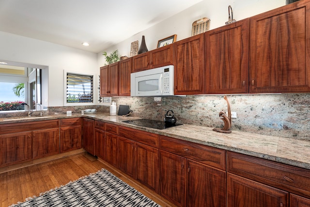 kitchen featuring a sink, backsplash, black electric stovetop, and white microwave