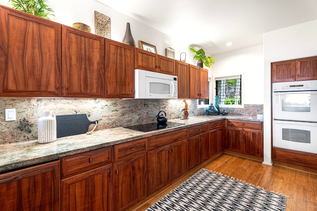 kitchen featuring white appliances, light wood-style flooring, light stone counters, and decorative backsplash