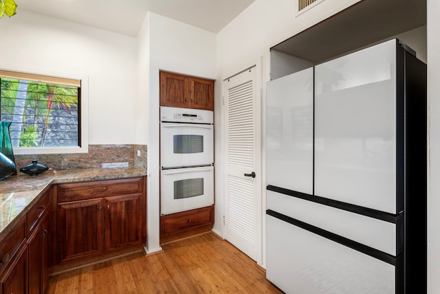 kitchen featuring white double oven, light wood-type flooring, and tasteful backsplash