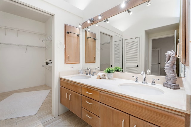 full bathroom with double vanity, a spacious closet, and a sink