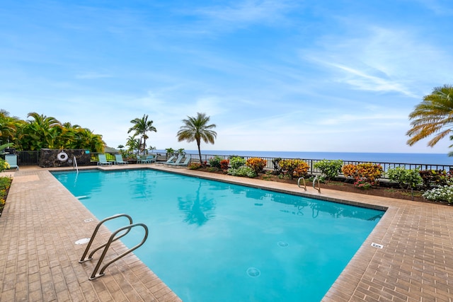 community pool with a water view and fence