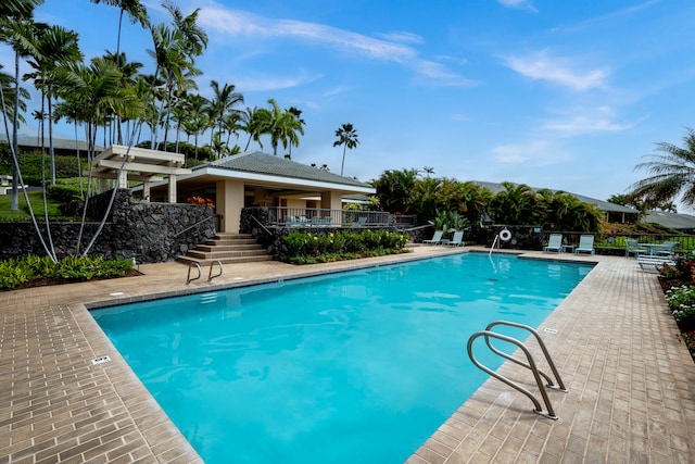 community pool with a patio area and fence