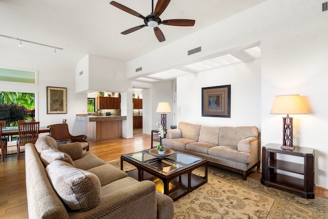 living area with light wood-style flooring, visible vents, and ceiling fan